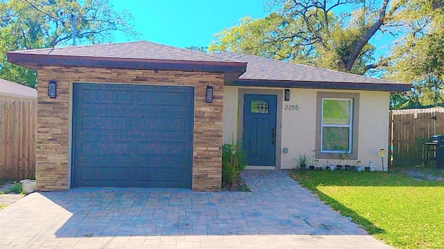 view of front of property featuring decorative driveway, an attached garage, a front lawn, and fence