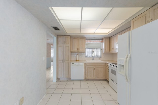 kitchen featuring white appliances, visible vents, light countertops, light brown cabinets, and a sink