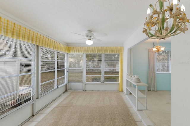 unfurnished sunroom featuring ceiling fan with notable chandelier