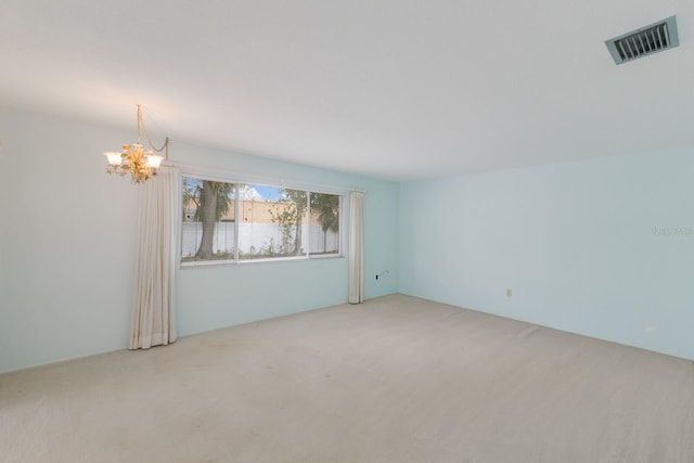 spare room featuring light carpet, visible vents, and a notable chandelier