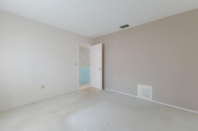 spare room featuring visible vents and light colored carpet