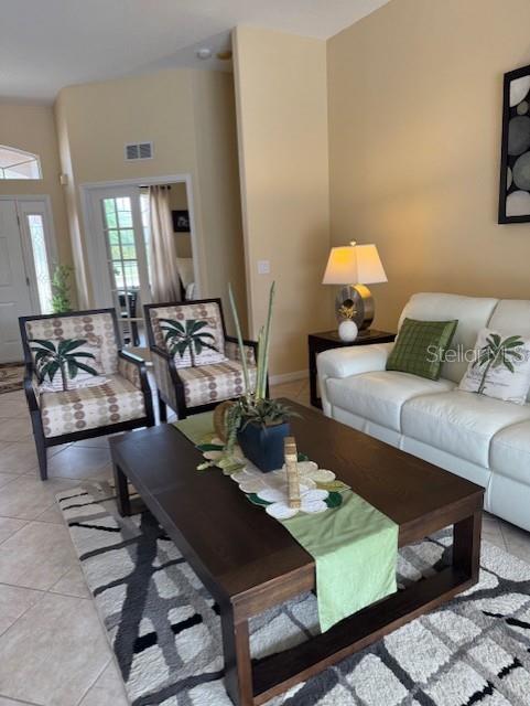 living area featuring light tile patterned floors, visible vents, and baseboards