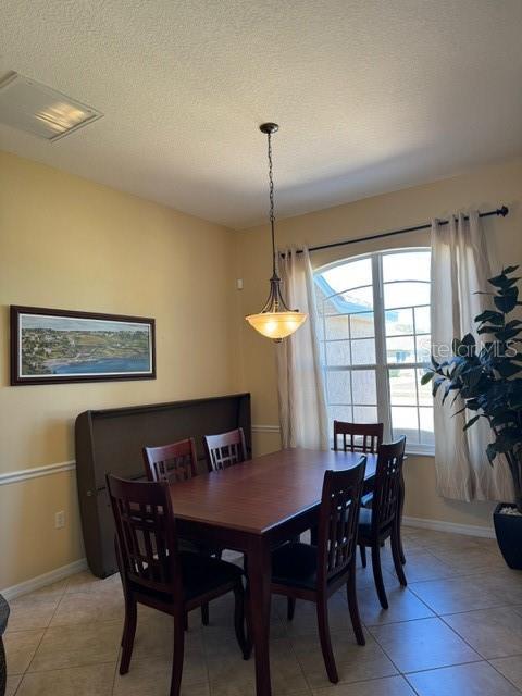 dining area featuring a textured ceiling, light tile patterned floors, and baseboards