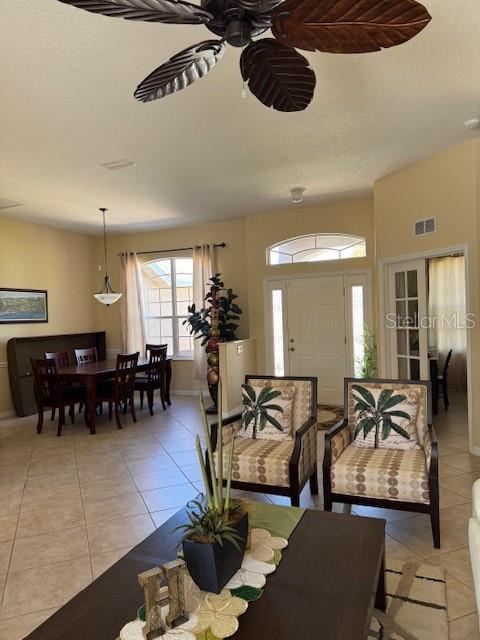 living room with light tile patterned floors, visible vents, and a ceiling fan