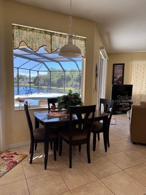 dining space featuring light tile patterned floors, a sunroom, and baseboards