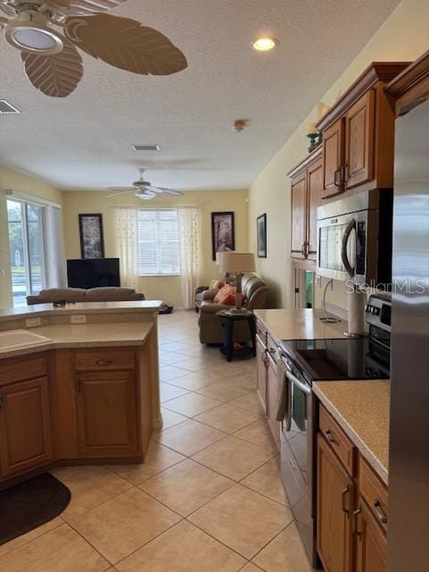 kitchen with brown cabinetry, ceiling fan, stainless steel appliances, and open floor plan