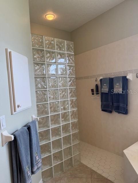 bathroom with a walk in shower, a textured ceiling, and tile patterned floors