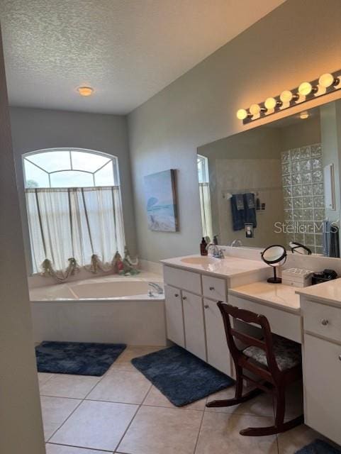 full bathroom with tile patterned flooring, a garden tub, a textured ceiling, and vanity