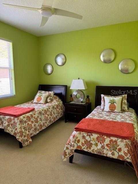 carpeted bedroom with a ceiling fan and a textured ceiling