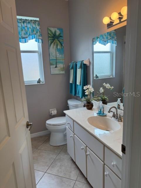 bathroom with baseboards, vanity, toilet, and tile patterned floors