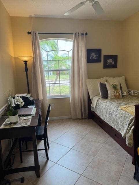 bedroom featuring ceiling fan, a textured ceiling, baseboards, and light tile patterned floors