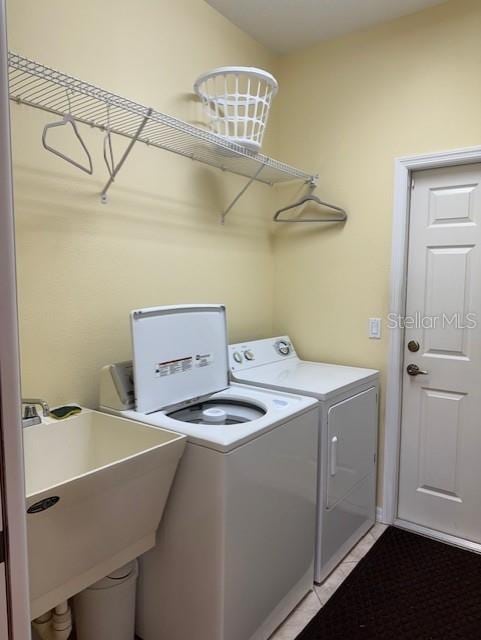 washroom with laundry area, washer and clothes dryer, and a sink