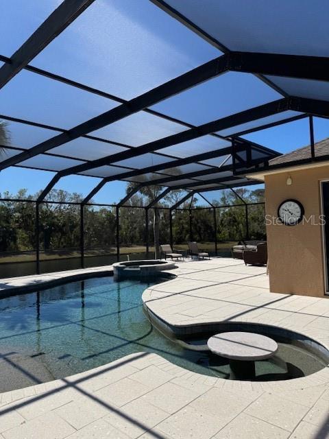 view of pool with glass enclosure, a patio area, and a pool with connected hot tub