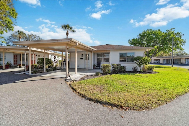 ranch-style house with an attached carport, driveway, and a front lawn