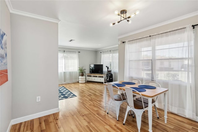 dining room with light wood-type flooring, a healthy amount of sunlight, and crown molding