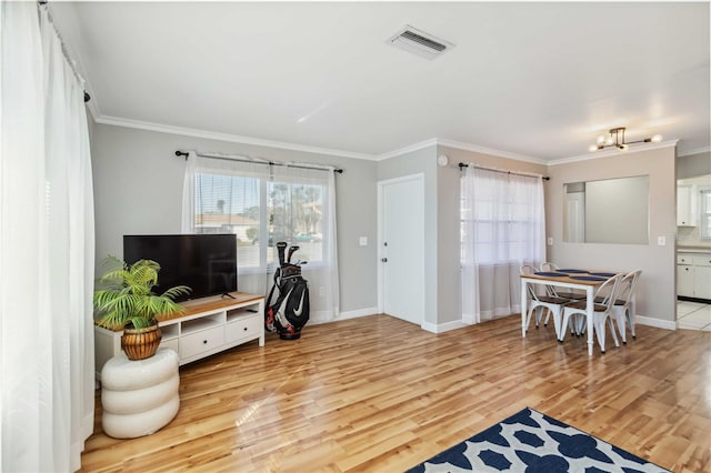 living area featuring visible vents, baseboards, light wood-style floors, and ornamental molding