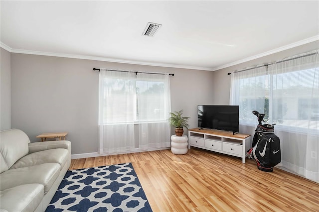 living area featuring plenty of natural light, wood finished floors, visible vents, and ornamental molding