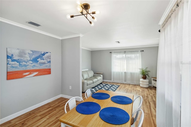 living area featuring visible vents, a notable chandelier, wood finished floors, and crown molding