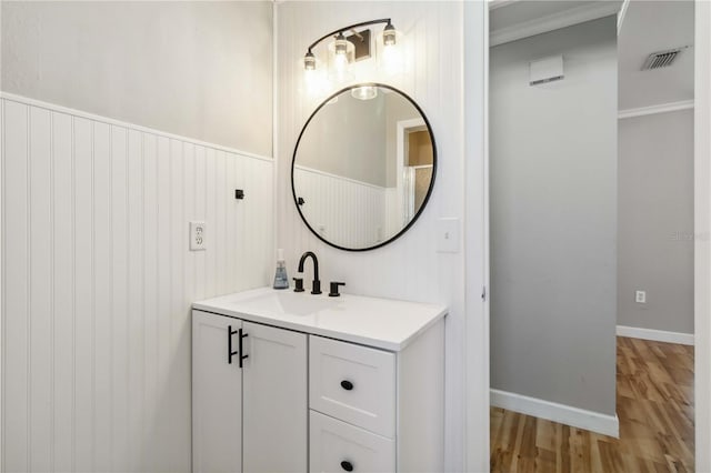 bathroom with visible vents, wood finished floors, wainscoting, baseboards, and vanity