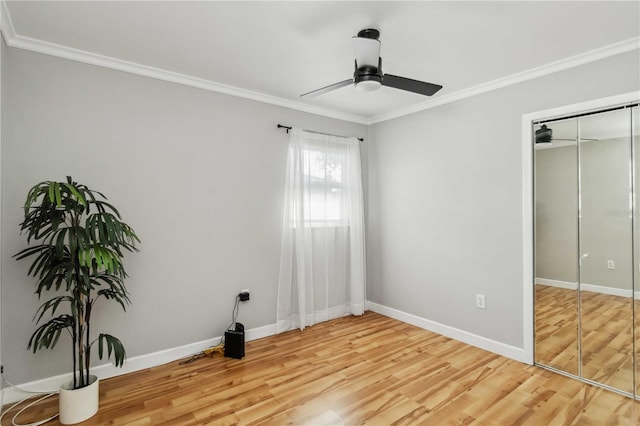 unfurnished bedroom featuring a ceiling fan, baseboards, light wood finished floors, ornamental molding, and a closet