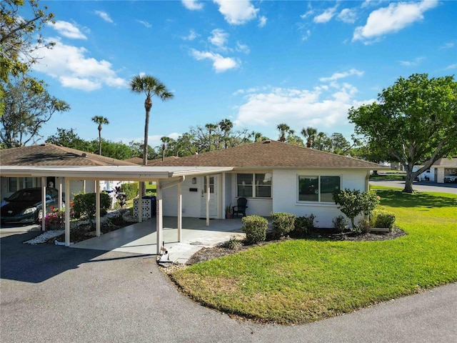 ranch-style house featuring driveway, an attached carport, and a front yard