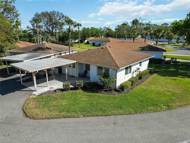 view of front of home featuring an attached carport, a front yard, roof with shingles, and stucco siding