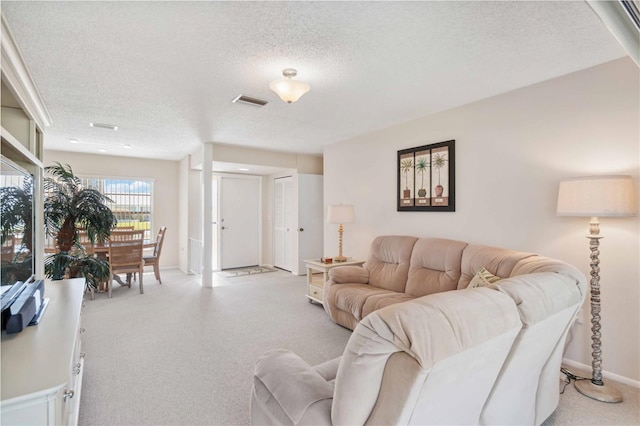 living area featuring visible vents, light carpet, a textured ceiling, and baseboards