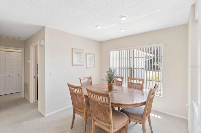 dining space featuring visible vents, baseboards, a textured ceiling, and light carpet