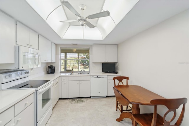 kitchen with white appliances, light countertops, a raised ceiling, and a sink