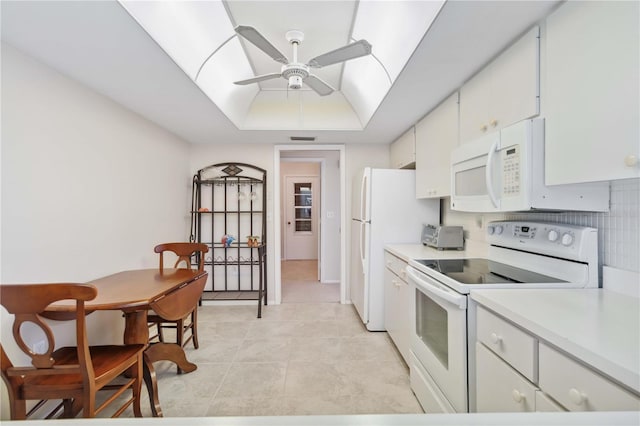 kitchen featuring white appliances, white cabinetry, light countertops, and a tray ceiling