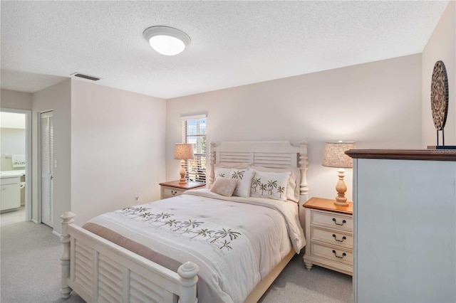 bedroom featuring light colored carpet, visible vents, ensuite bathroom, and a textured ceiling