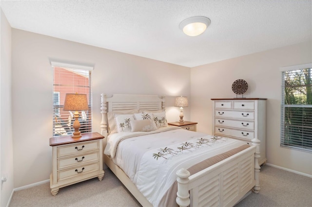 bedroom featuring a textured ceiling, baseboards, and light carpet