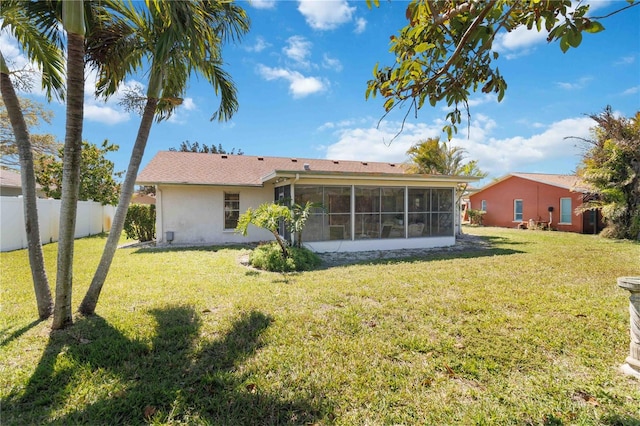 back of property featuring a yard, fence, a sunroom, and stucco siding