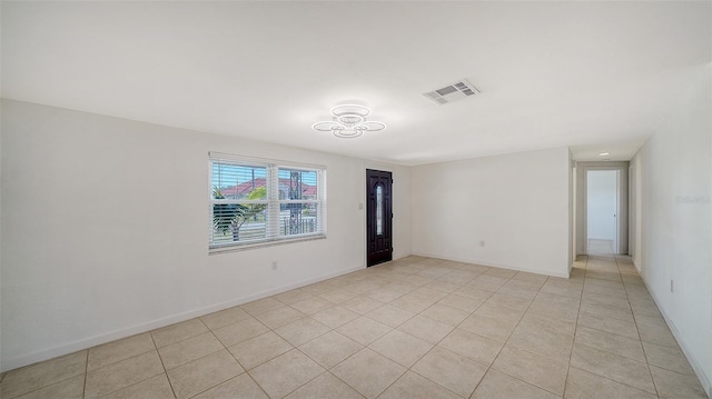 empty room featuring light tile patterned floors, baseboards, and visible vents