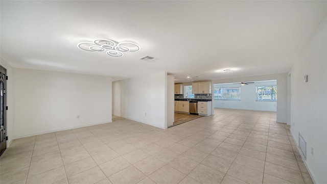 unfurnished living room featuring light tile patterned floors, baseboards, visible vents, a sink, and ceiling fan