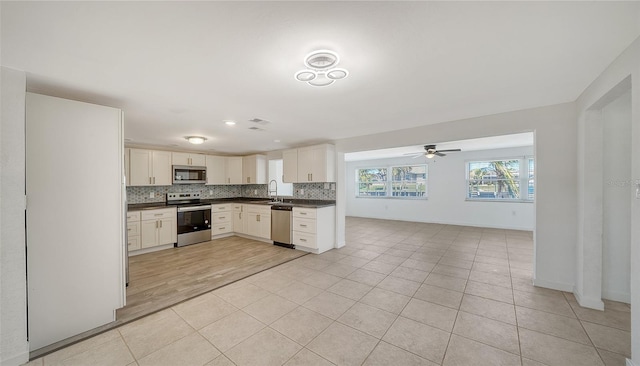 kitchen featuring dark countertops, decorative backsplash, stainless steel appliances, and light tile patterned floors