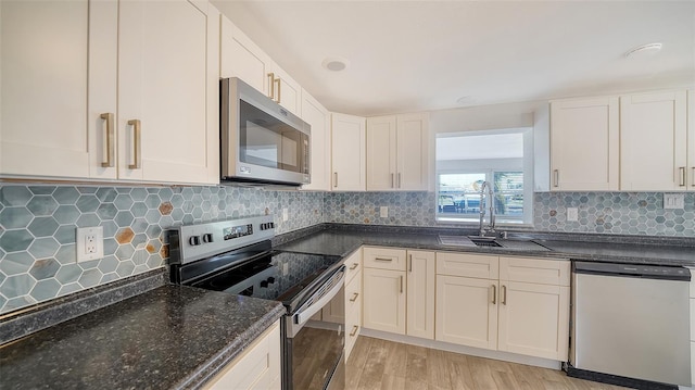 kitchen featuring backsplash, appliances with stainless steel finishes, light wood-style floors, and a sink