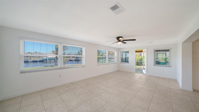 unfurnished room with light tile patterned floors, a healthy amount of sunlight, visible vents, and baseboards