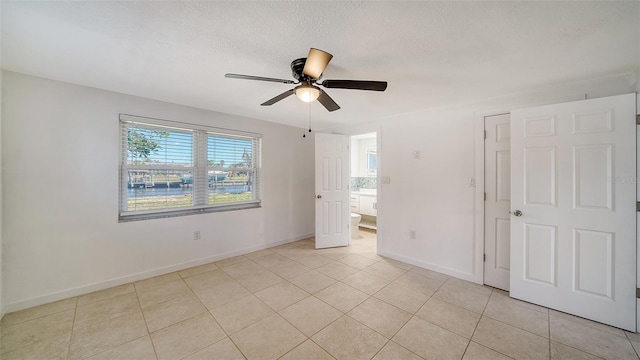 unfurnished room featuring light tile patterned floors, a textured ceiling, and baseboards