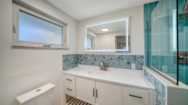 bathroom with tasteful backsplash, a healthy amount of sunlight, toilet, and vanity