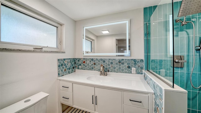 full bathroom with backsplash, toilet, vanity, and a tile shower