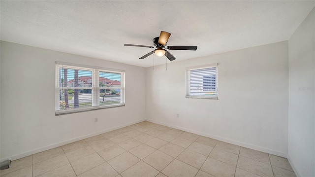 spare room featuring light tile patterned floors, baseboards, a textured ceiling, and ceiling fan