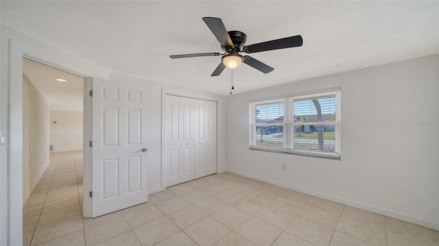 unfurnished bedroom with light tile patterned floors, a closet, baseboards, and a ceiling fan