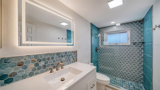 full bath with tasteful backsplash, toilet, tiled shower, and vanity