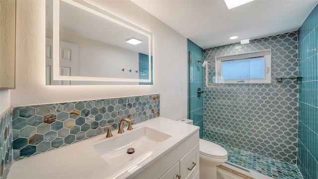 full bathroom with backsplash, toilet, vanity, and a tile shower