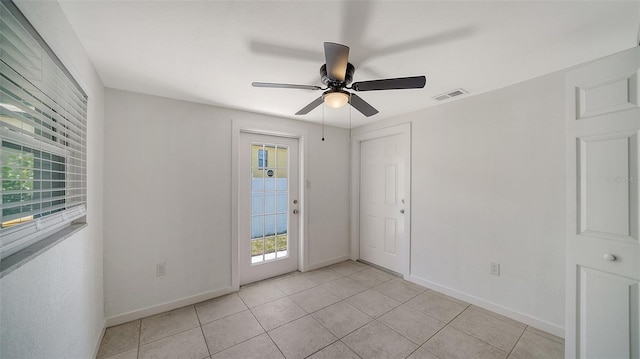 empty room with light tile patterned floors, baseboards, visible vents, and ceiling fan