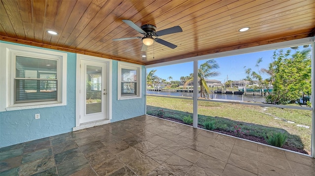 unfurnished sunroom with a ceiling fan, wood ceiling, and a water view