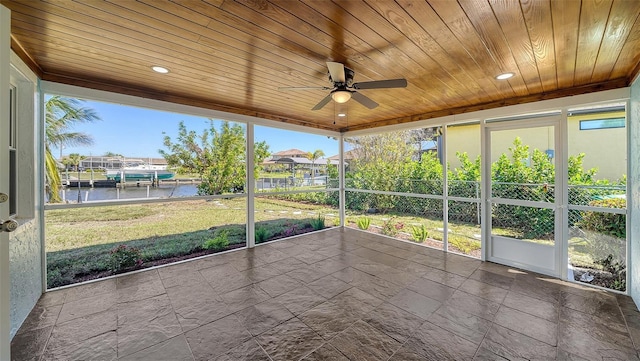 unfurnished sunroom with wooden ceiling, a ceiling fan, and a water view