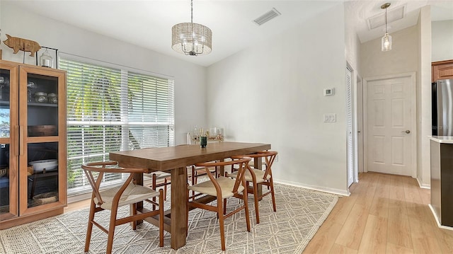 dining area with visible vents, light wood-style flooring, baseboards, and an inviting chandelier