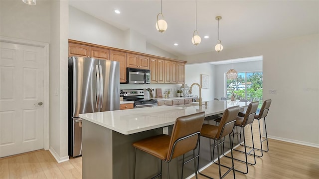 kitchen featuring a kitchen island with sink, a sink, vaulted ceiling, light countertops, and appliances with stainless steel finishes